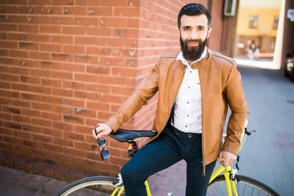 Bisiklet bir tuğla zemin üzerine oturan bir sakallı genç şık adam — Stok fotoğraf