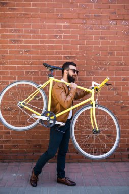 Bir düzenleme Bisiklet sakallı adam. Onun Bisiklet omuz üzerinde taşıyan ve açık havada yürürken kameraya bakarak adam kendine güvenen genç sakallı.