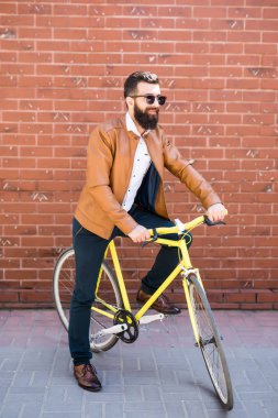 Serin genç sakallı hippi yanı sıra tuğla duvar sokak düzenleme bisikletle