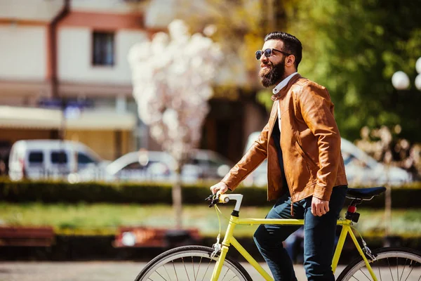 Een jonge stijlvolle hipster poseren naast zijn fiets op straat stad — Stockfoto