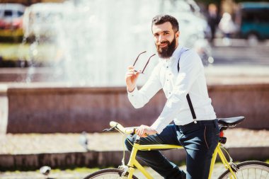 Yakışıklı hipster şehir binmek bisiklet tarafından zevk güneş gözlüğü.