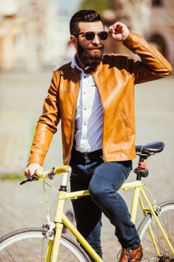 Kendine güvenen genç sakallı adam güneşli Caddesi boyunca onun bisiklet sürme güneş gözlüğü