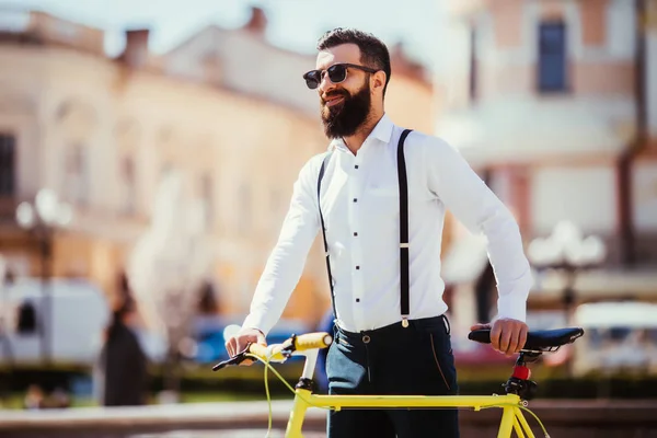 Jovem homem elegante vai trabalhar de bicicleta. hipster com uma bicicleta fixie na rua. homem barbudo olhando embora enquanto andava de bicicleta ao ar livre — Fotografia de Stock