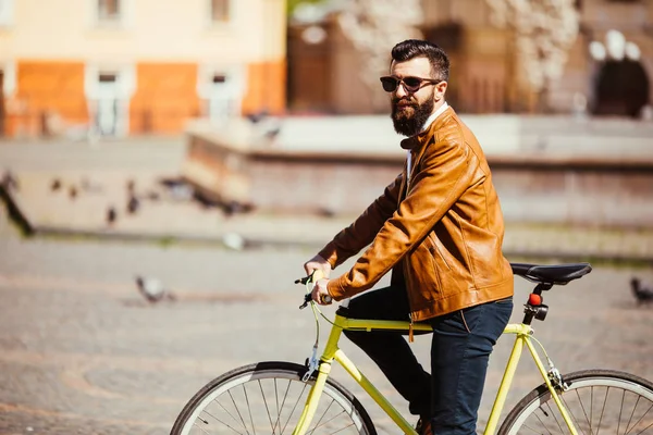 Hipster homem andando em uma bicicleta fixie nas ruas ensolaradas da cidade . — Fotografia de Stock