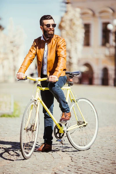 Красивый бородатый молодой человек в солнечных очках на велосипеде в городе. Концепция велосипеда — стоковое фото