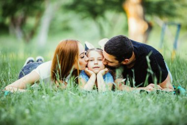 Ailesi kızlarının yaz parkta yalan ile. Aile yeşil çim üzerinde yalan.