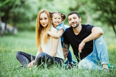 Mutluluk ve uyum içinde aile hayatı. Mutlu aile kavramı. Genç anne ve babası ile kızları parkta. Mutlu bir aile birlikte yeşil çimenlerin üzerinde dinlenme. Aile açık eğleniyor