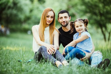 Mutlu anne, baba ve yaz parkta oynayan kız