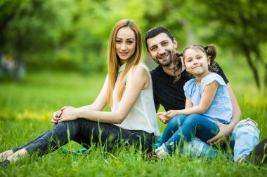 Mutlu anne, baba ve yaz parkta oynayan kız