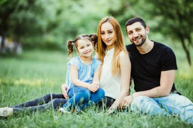 Mutlu anne, baba ve kız parkta oynarken. Aile açık hava yaşam tarzı ile güzellik doğa sahne. Eğleniyor birlikte çimenlerin üzerinde dinlenme mutlu bir aile. Mutluluk ve uyum içinde aile hayatı.