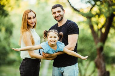 Mutlu anne, baba ve kızı toghether parkta oynarken. Kızı anne elinde uçmayı deneyin.