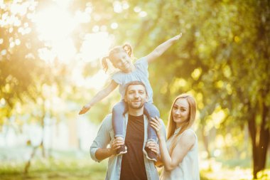 mutlu aile anne ve baba holding kızı onun geri ve parkta iyi eğlenceler.