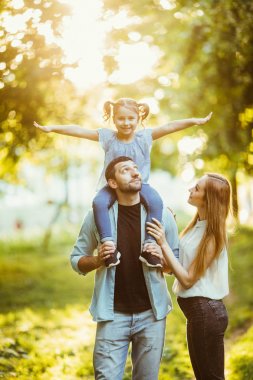 mutlu aile anne ve baba holding kızı onun geri ve parkta iyi eğlenceler.