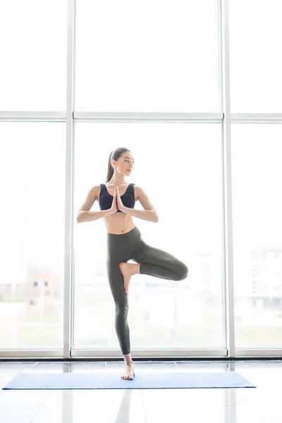 Young beautiful yoga posing on a panoramic windows on city background — Stock Photo, Image
