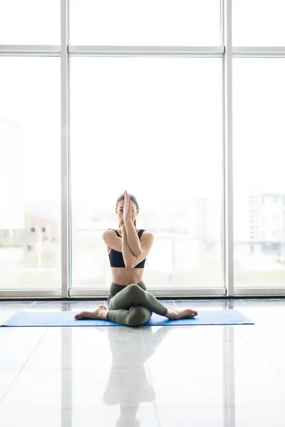 Ung vacker kvinna som mediterar samtidigt öva yoga med stadsutsikt i bakgrunden. — Stockfoto