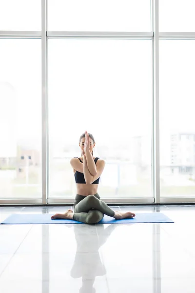 Joven hermosa mujer meditando mientras practica yoga con vista a la ciudad en el fondo . —  Fotos de Stock