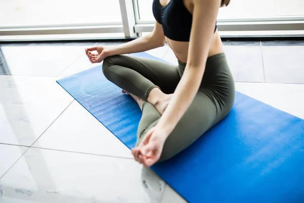 Yoga girl mediterar inomhus och göra en zen symbol med hennes hand. Närbild av kvinna kropp i yoga posera. — Stockfoto