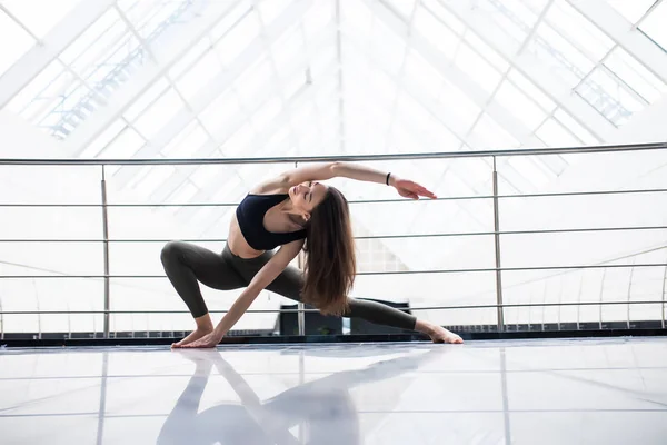 Hermosa práctica de yoga mujer en un fondo sala de entrenamiento. Concepto de yoga . — Foto de Stock