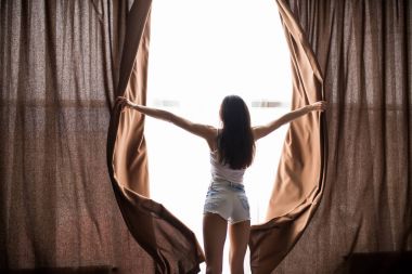 Kadın, uyan ve güneş ışığı almak için sabah perdeleri açık