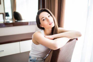 Evde rahat sandalye üzerinde oturan genç kadın