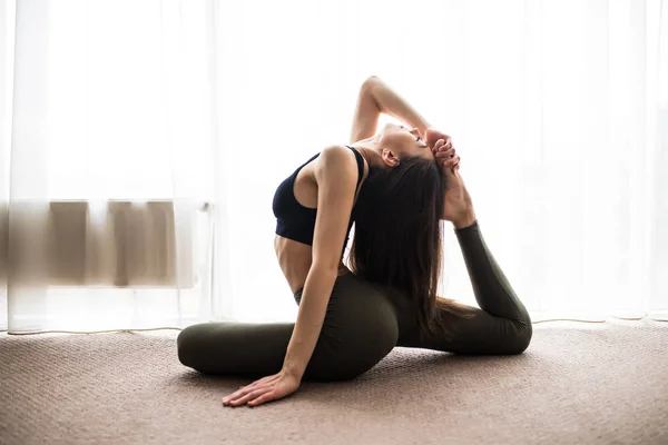 Jonge vrouw beoefenen van yoga thuis op verdieping in de ochtend — Stockfoto