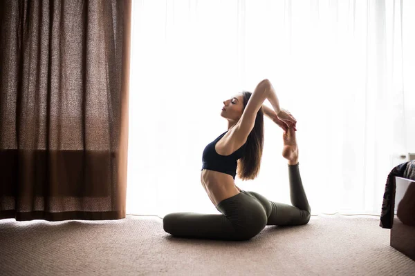 Ung attraktiv leende kvinna praktisera yoga, sitter i ett ben King Pigeon motion, Eka Pada Rajakapotasana utgör hemma — Stockfoto