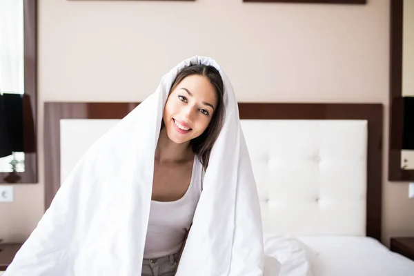 笑顔の女性は、彼女のベッドルームで羽布団の下。毛布の下の美しい若い女性のポートレート、クローズ アップ。幸せな朝 — ストック写真