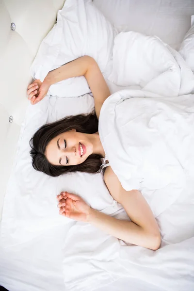 Женщина лежит в постели и вытягивает руки после пробуждения утром — стоковое фото