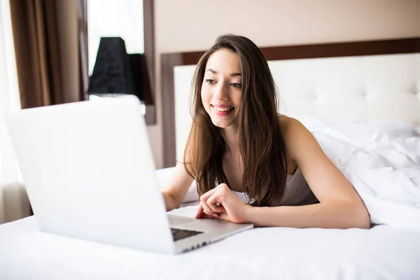 Mujer sonriendo y mirando delante de ella mientras usa su tarjeta de crédito con su computadora portátil . — Foto de Stock