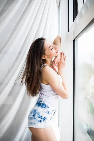 Закрыть глаза на счастливую женщину, открывающую утром шторы на окнах — стоковое фото