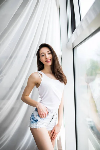 Vista lateral de una mujer feliz abriendo cortinas de una ventana y disfrutando de un nuevo día con una luz cálida del aire libre —  Fotos de Stock