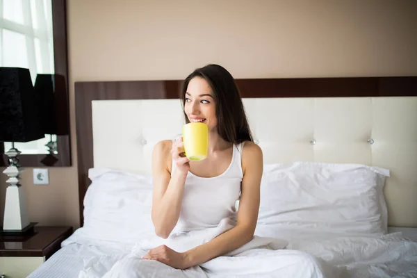 Piękna kobieta, picie kawy, siedząc na łóżku w domu w godzinach porannych — Zdjęcie stockowe
