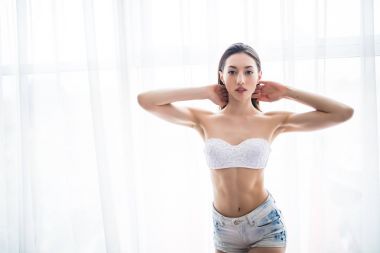 Perdeler pencere evde, iç tutan genç bir kadın arkadan görünüş.