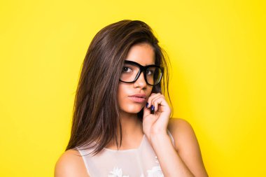 Gülümseyen güzel genç kadın portresi. Kız ile gözlük takıyor. Sarı arka plan.