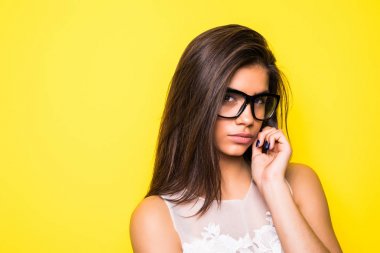 Gülümseyen güzel genç kadın portresi. Kız ile gözlük takıyor. Sarı arka plan.