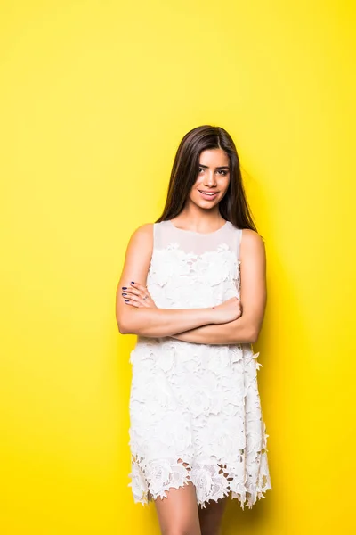 Porträtt av en vacker ung kvinna witn korsade händer leende på gul bakgrund — Stockfoto