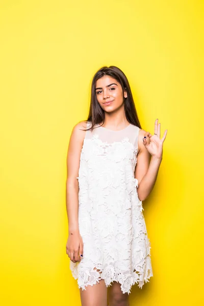 Glückliche junge Frau zeigt ok Zeichen mit den Fingern ein Augenzwinkern isoliert auf einem gelben Hintergrund — Stockfoto