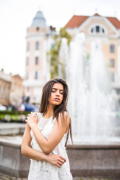 Joven hembra caucásica de pie cerca de la fuente. Primer plano retrato mujer al aire libre . —  Fotos de Stock