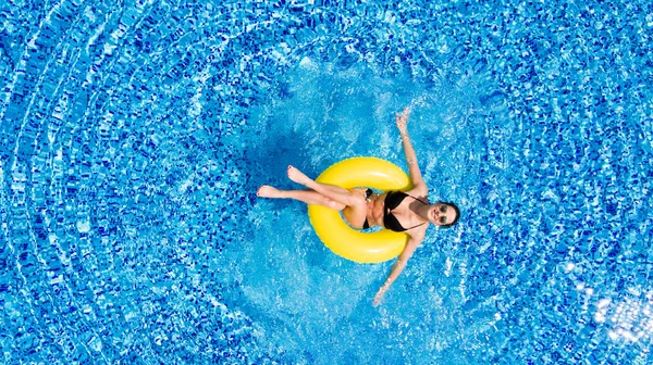 Vakantie concept. Bovenaanzicht van slanke jonge vrouw in bikini op het gele air opblaasbare ring in het grote zwembad. — Stockfoto