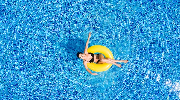 Luchtfoto van jonge brunette vrouw op de opblaasbare grote gele in het zwembad zwemmen. Bovenaanzicht van slanke dame ontspannen op haar vakantie. — Stockfoto