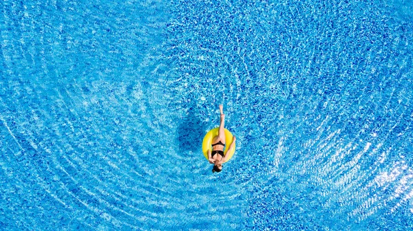 Νεαρή όμορφη γυναίκα είναι χαλαρώνοντας στην πισίνα με δαχτυλίδι καουτσούκ κίτρινο. — Φωτογραφία Αρχείου