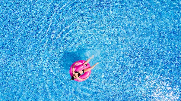 Загорелая девушка сидит на надувном матрасе фламинго в бассейне сверху — стоковое фото
