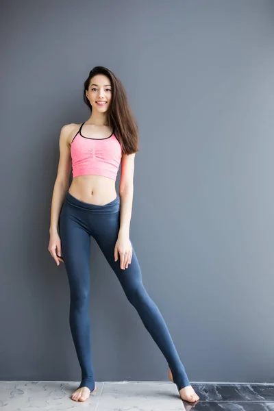 Full-length portrait of a young cheerful woman standing on gray background — Stock Photo, Image