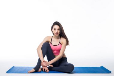 Beyaz arka planda yalnız başına yoga yapan genç bir kadın.