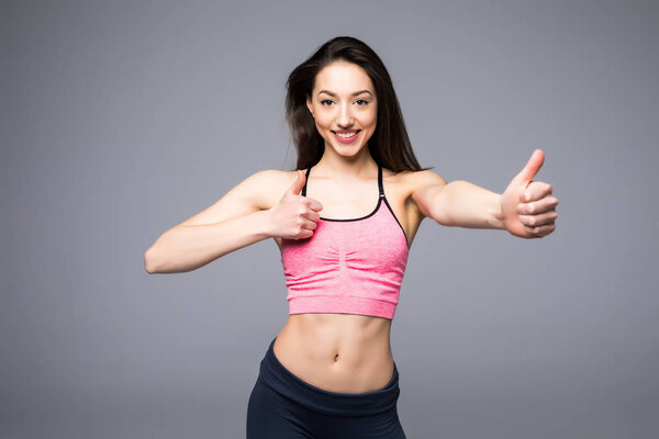 Beautiful fitness woman showing thumb up on white background