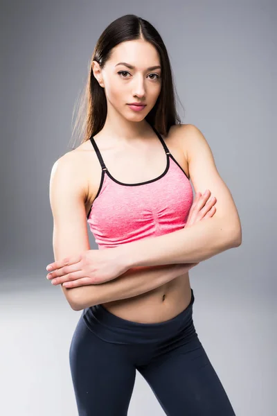 Fitness žena ve sportovním oblečení pózuje na šedém pozadí, studio zastřelil — Stock fotografie