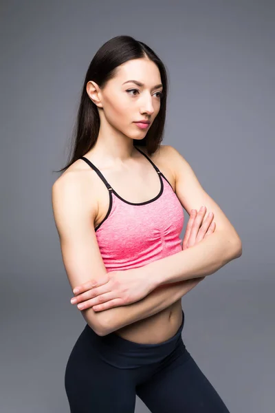 Fitness woman in sports clothes posing on gray background, studio shot — Stock Photo, Image