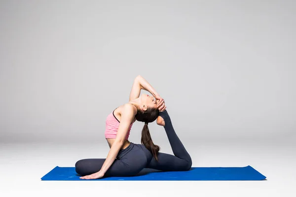 Jeune femme séduisante pratiquant le yoga, debout dans différents exercices de yoga, portant des vêtements de sport isolés sur fond gris. Série de Yoga concept de position — Photo