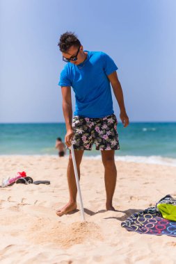 Genç adam yüklemek bir plaj kum güneş şemsiyesi içinde