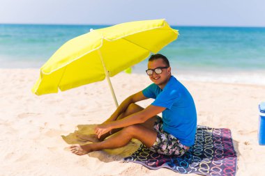 Güneş havlu güneş şemsiyesi altında erkekte tembellik yapmak zevk almak tembel zaman sahilde
